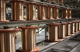 Rows of copper wire spools on industrial racks inside a manufacturing or processing facility.