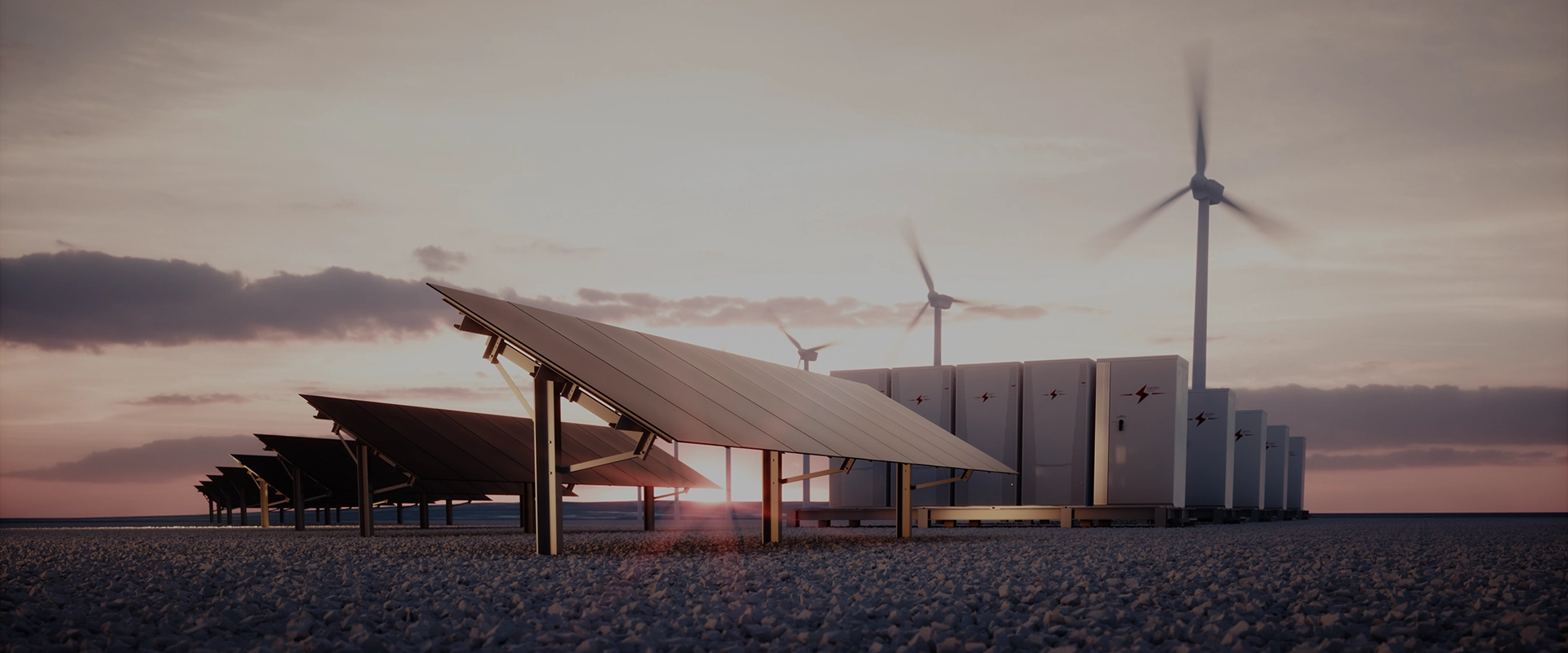 An array of solar panels and a large bank of industrial batteries with wind turbines spinning in the background under a dramatic sunset sky, representing renewable energy and storage.